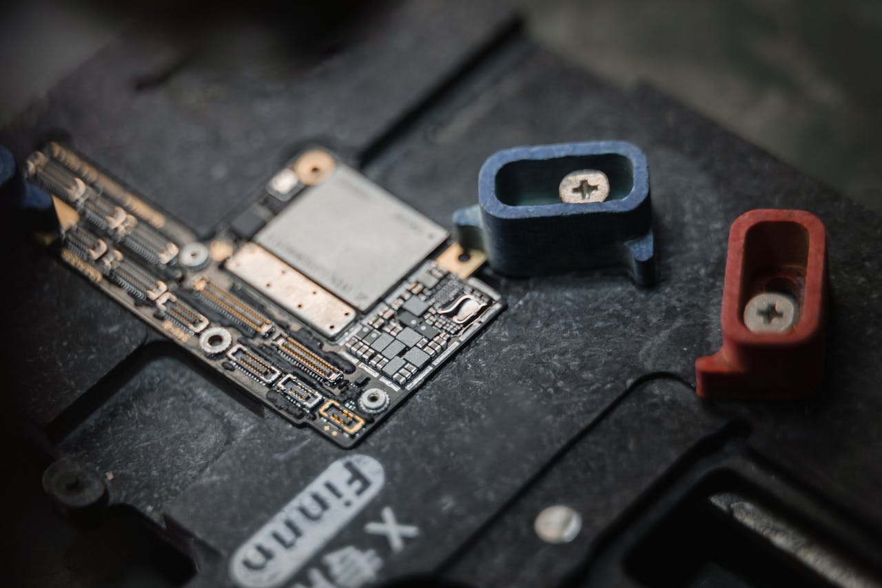 Detailed view of a circuit board with components and colored screws on a dark surface.